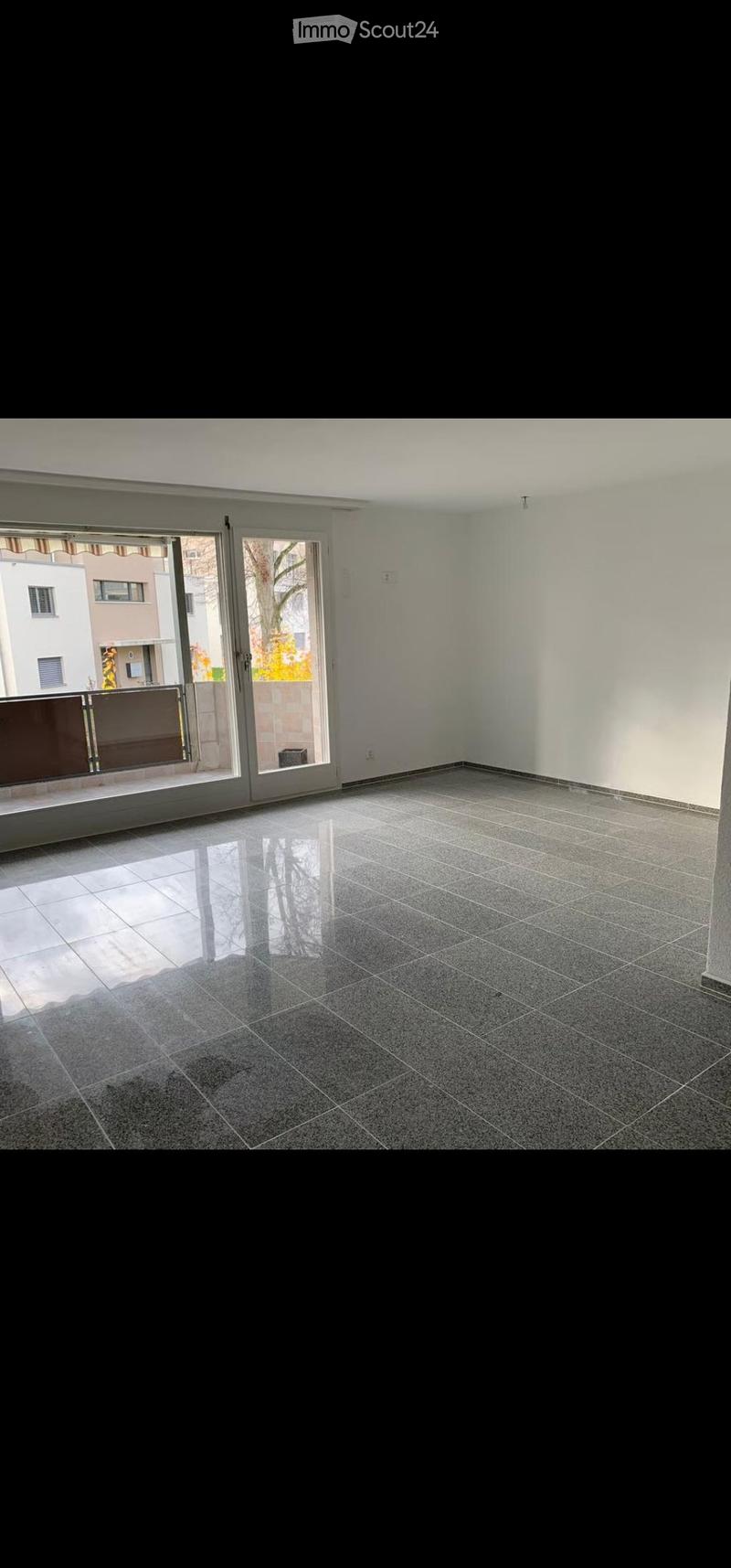 Empty room with tiled floor and large sliding glass doors leading to a balcony.