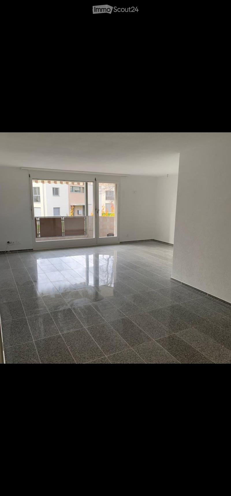Empty room with polished tile flooring, white walls, and large sliding glass doors leading to a balcony.