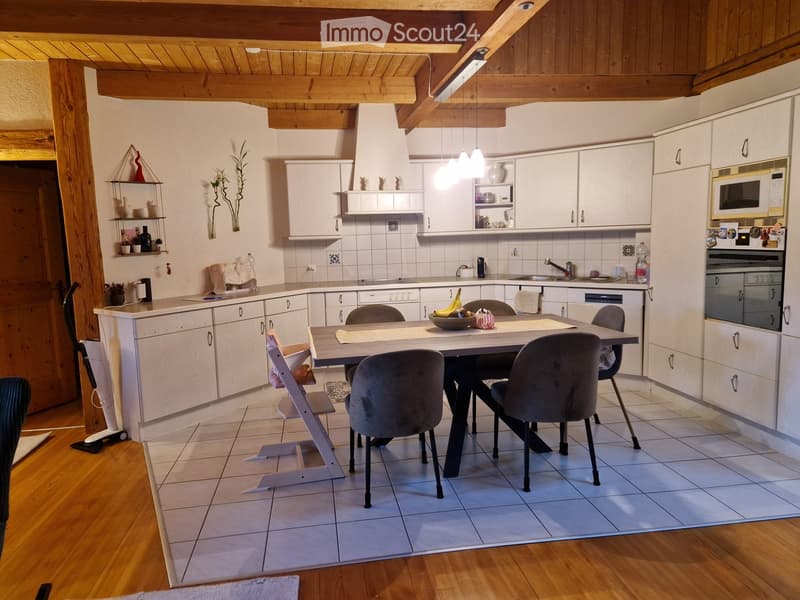 Bright kitchen with white cabinets, a central island, and a dining area. Includes a microwave, oven, and various kitchen appliances.