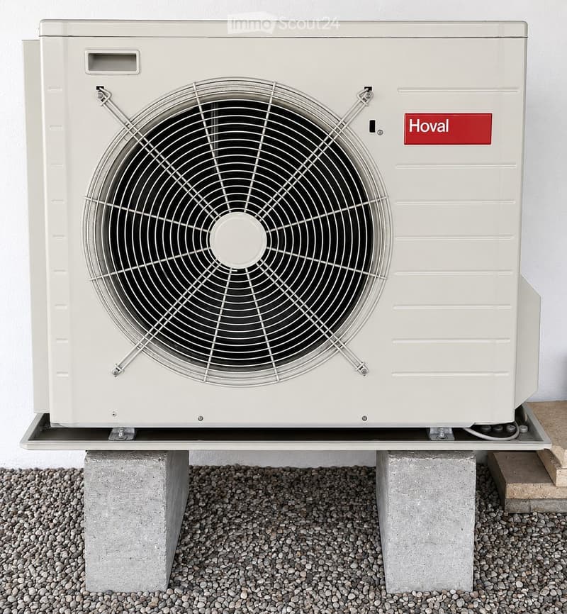 A white Hoval air conditioner unit mounted on a concrete base with a large fan on the front.