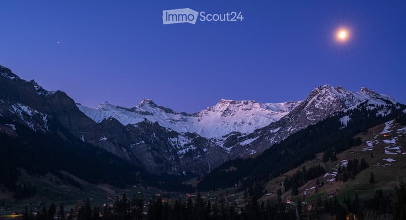 A serene mountain landscape at night, with snow-capped peaks and a small village nestled in the valley below.
