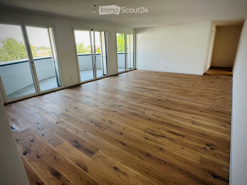 Empty room with wooden flooring and large glass sliding doors leading to a balcony.