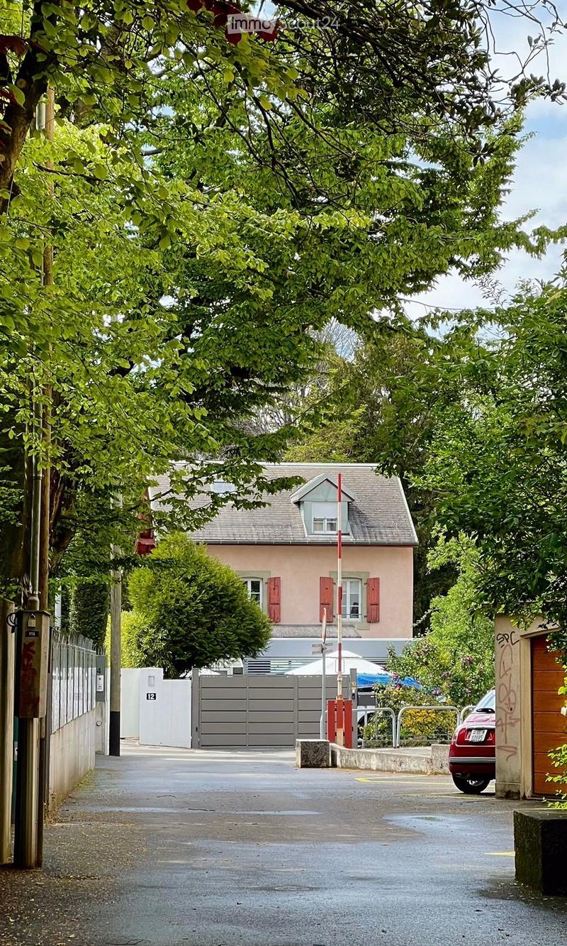 2 story house, pink paint, gray roof, gated entrance, driveway, small garden, grey gate, red car parked