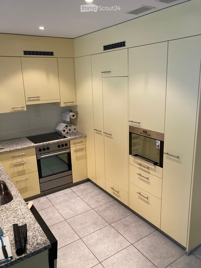 Modern kitchen with light-colored cabinets, granite countertops, and stainless steel appliances including two ovens and a sink.