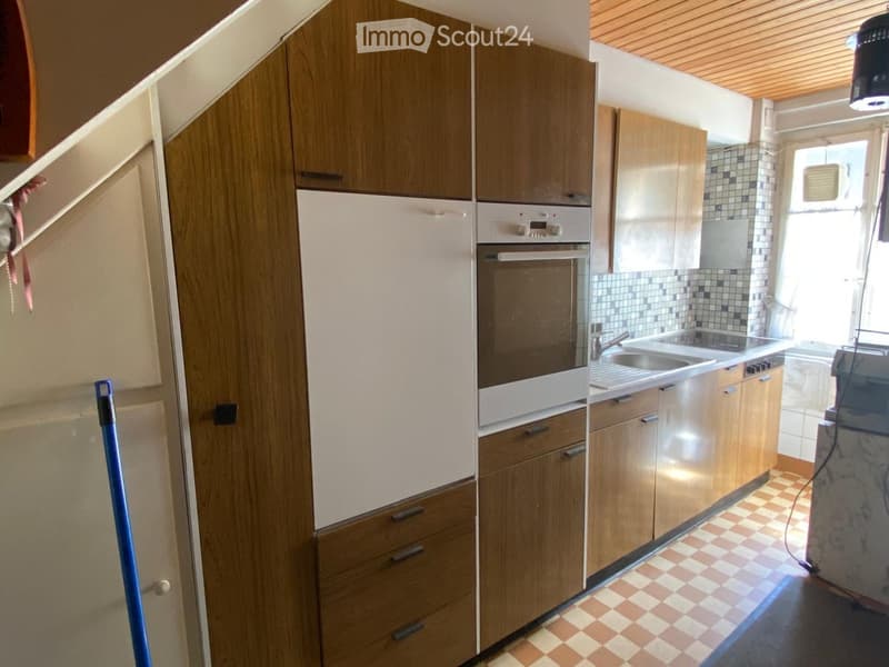 Modern kitchen with wooden cabinets, stainless steel appliances, and a checkered tile floor.