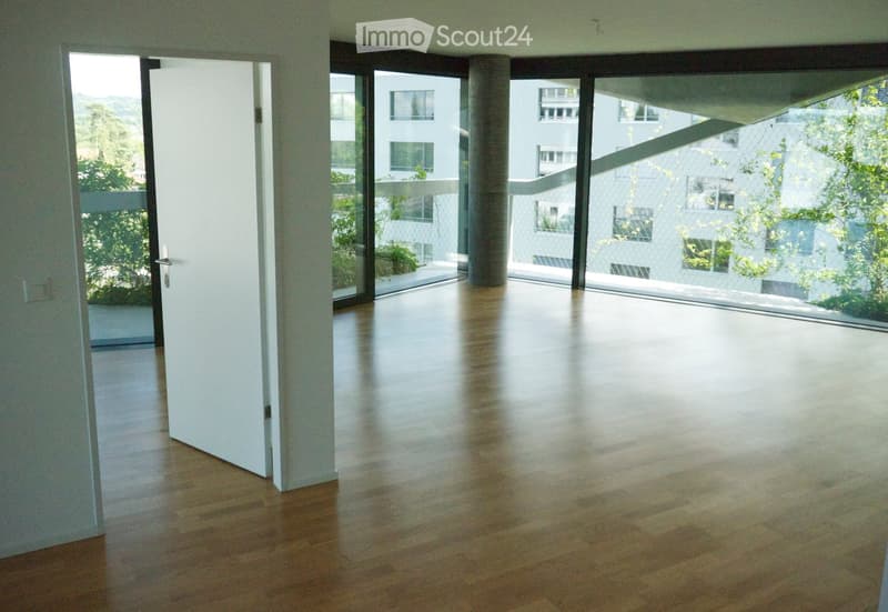 Empty room with wooden flooring, large glass sliding doors leading to a balcony, and white walls.