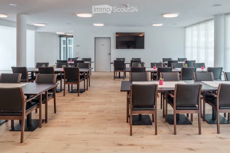 empty room, tables and chairs, parquet flooring, white walls, ceiling lights, white doors, television, potted plants