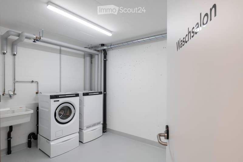 Utility room with white washing machine, white dryer, and a white sink.