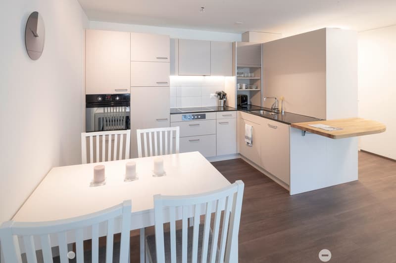 modern kitchen with dining area, white cabinets, wooden floor, large windows, kitchen appliances, dining table with chairs
