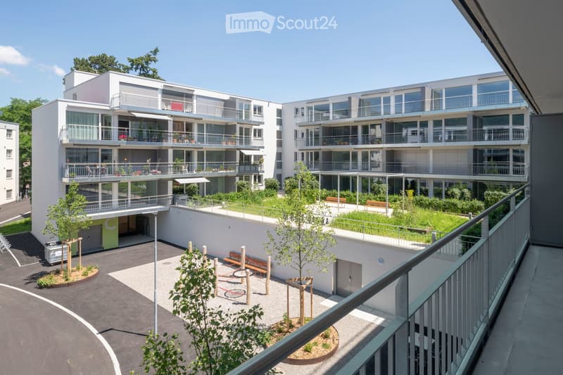 multi-story residential building, balconies, green spaces, playground