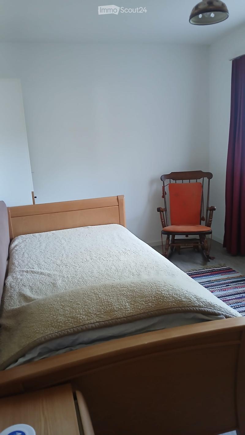A cozy bedroom with a wooden bed, a rocking chair, and a colorful rug on the floor.