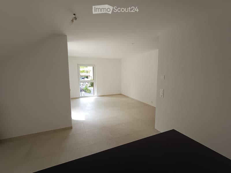 Empty room with tiled floor, white walls, and a large window with a view of the outside area.
