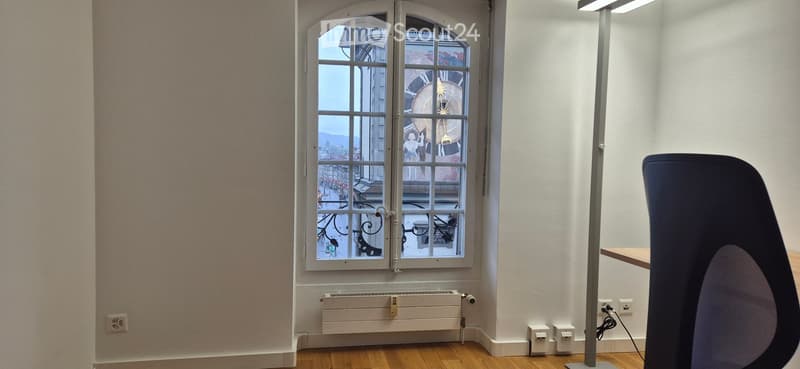 Empty room with wooden flooring, white walls, a large arched window with decorative glass, and a radiator below the window.