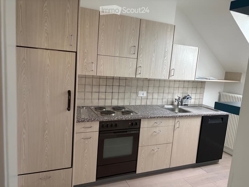 Modern kitchen with light wood cabinets, granite countertop, electric stovetop, oven, sink, and dishwasher.