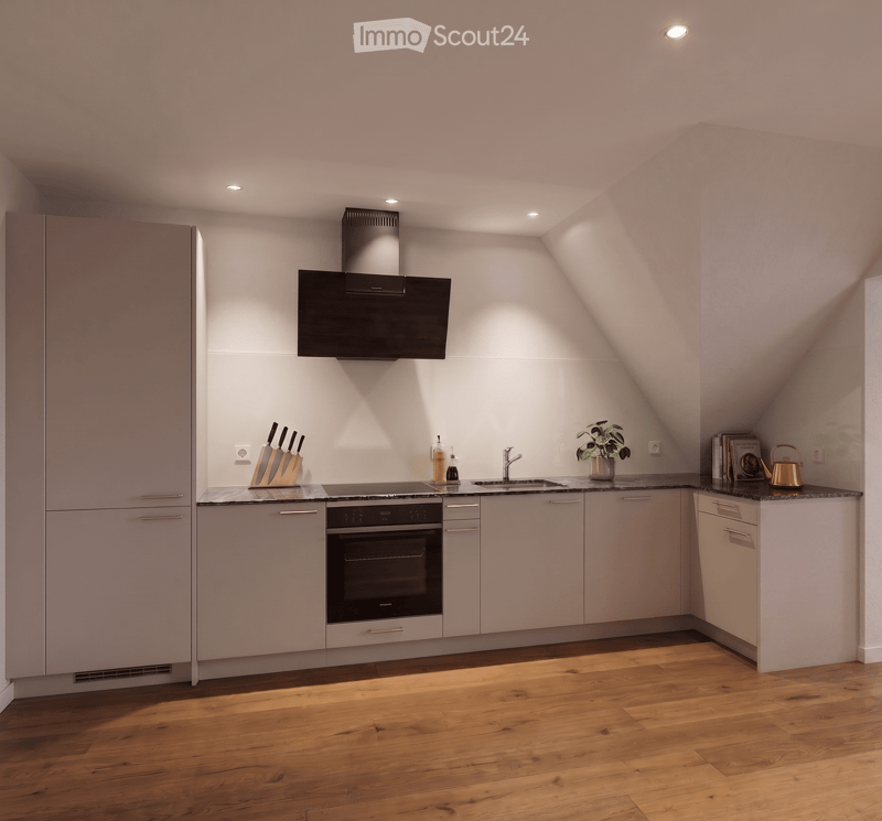 Modern kitchen with light grey cabinets, wooden flooring, and built-in appliances including a refrigerator, oven, and sink. Countertop features a knife block, bottle, plant, books, and a teapot.