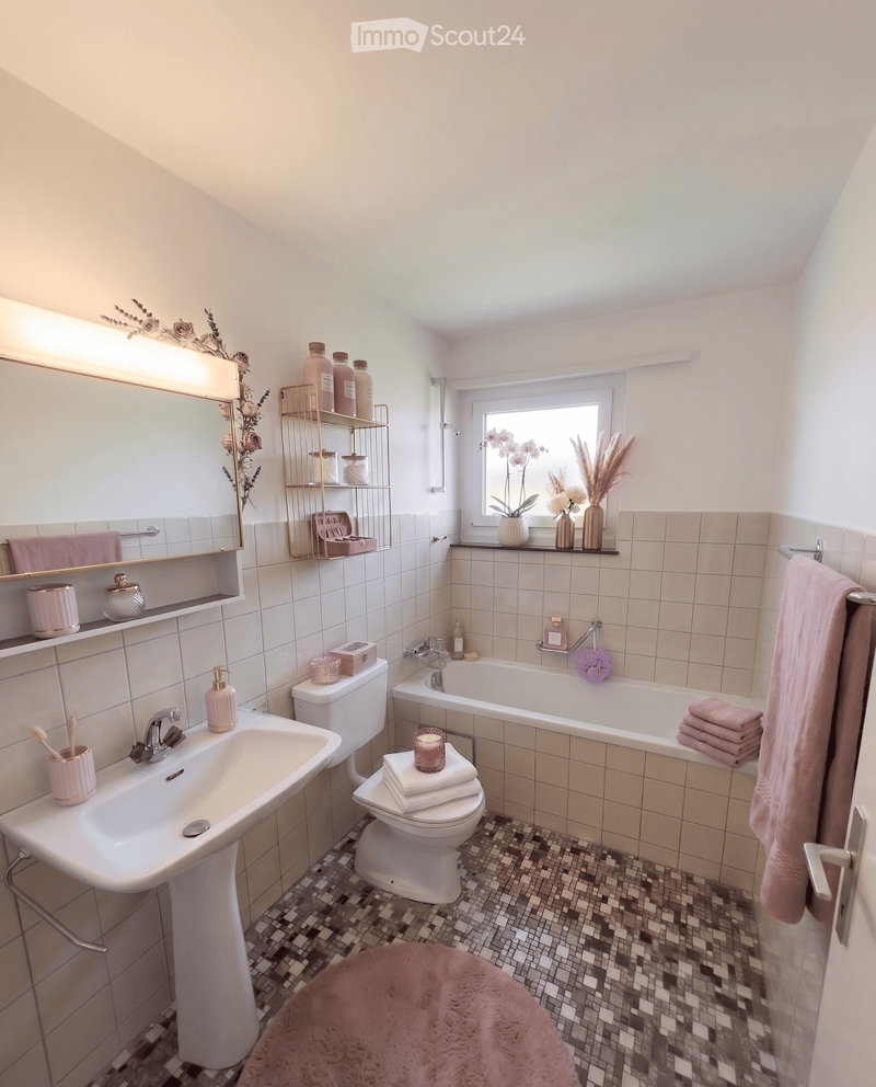 Bathroom with white tiles, a white sink, a toilet, a bathtub, a mirror, and a towel rack with towels.