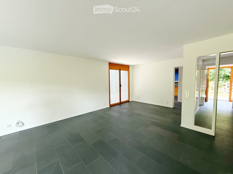 Empty room with white walls, dark grey tiled floor, and large sliding glass doors leading to an outdoor area.