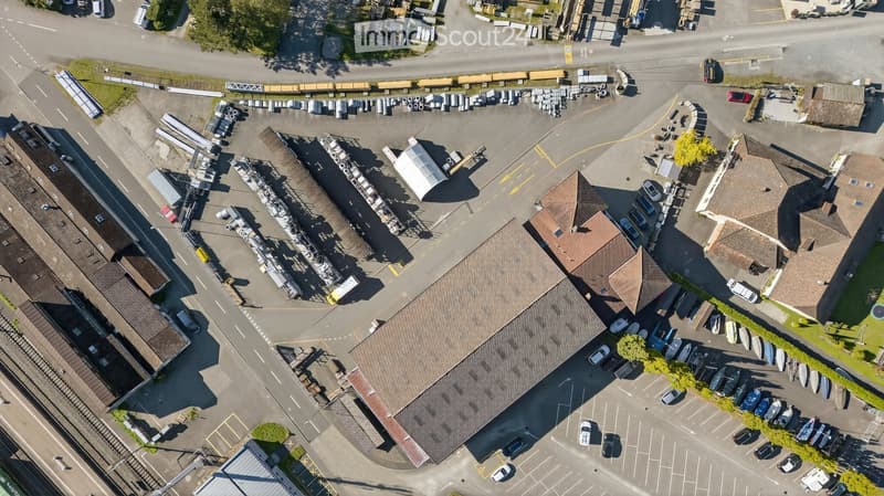 Several houses and warehouses with a parking lot and multiple cars parked.
