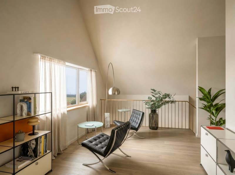 Modern, well-lit room with wooden flooring, large window with curtains, two black leather chairs, small glass table, bookshelf, floor lamp, and decorative plants.