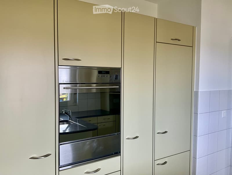 Modern kitchen with white cabinets, stainless steel oven, and black countertop.