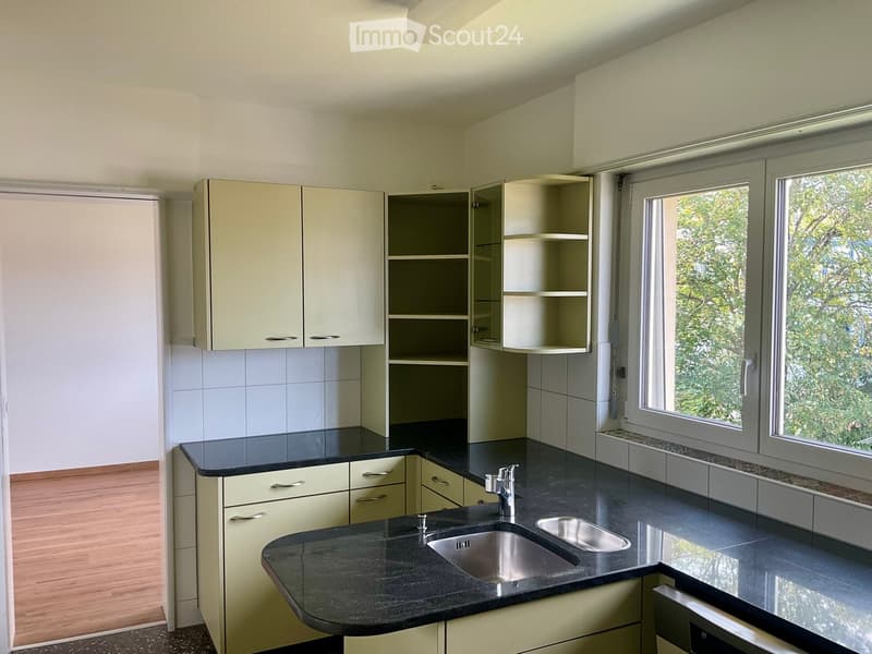 Modern kitchen with light-colored cabinets, black countertop, and stainless steel sink.