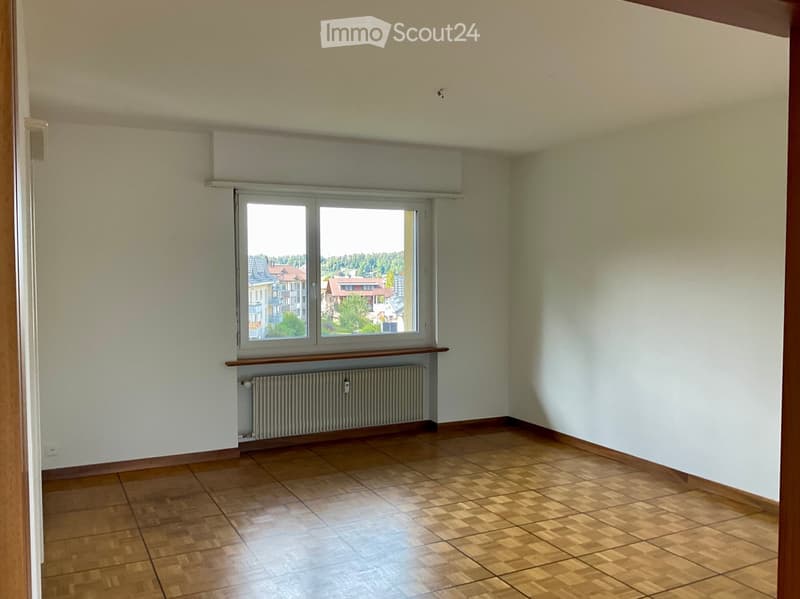 Empty room with wooden flooring, light-colored walls, a window with blinds, and a radiator below the window.