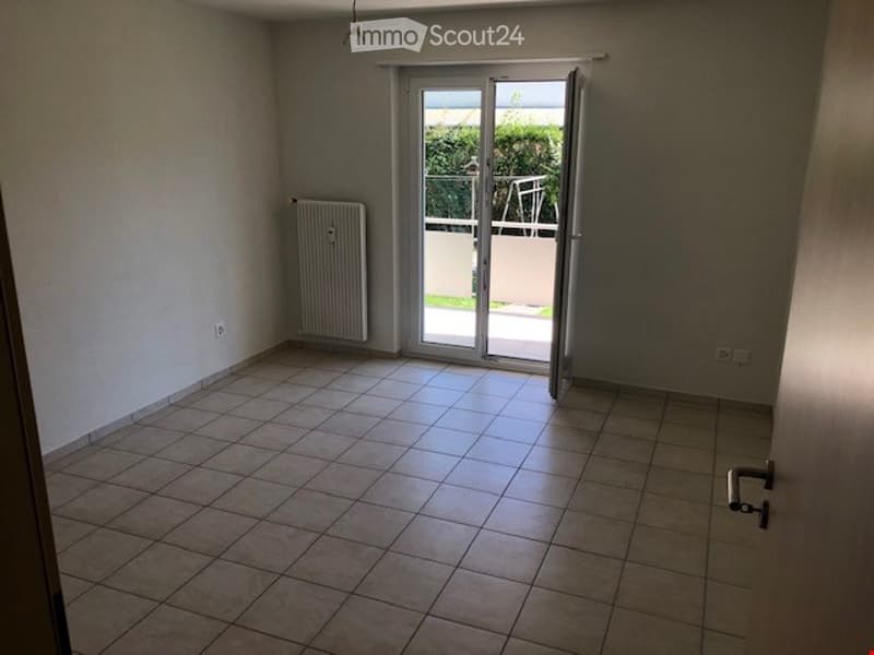 Empty room with tiled floor, white walls, radiator, and large sliding glass door opening to a balcony.