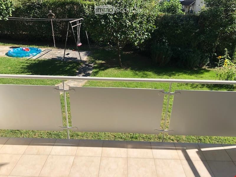 Balcony with tiled floor, white railing, overlooking a grassy backyard with a swing set and inflatable pool.