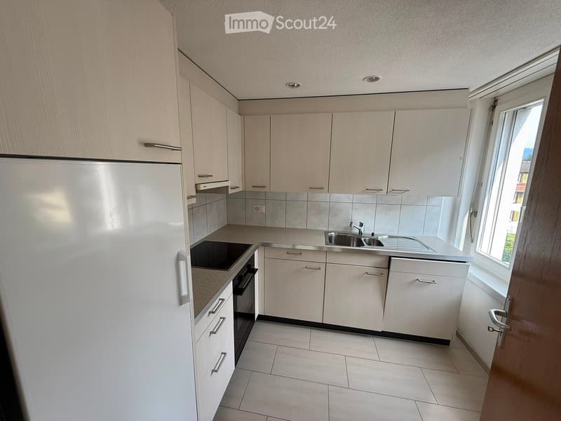 Modern kitchen with white cabinets, stainless steel appliances, and a tiled backsplash.