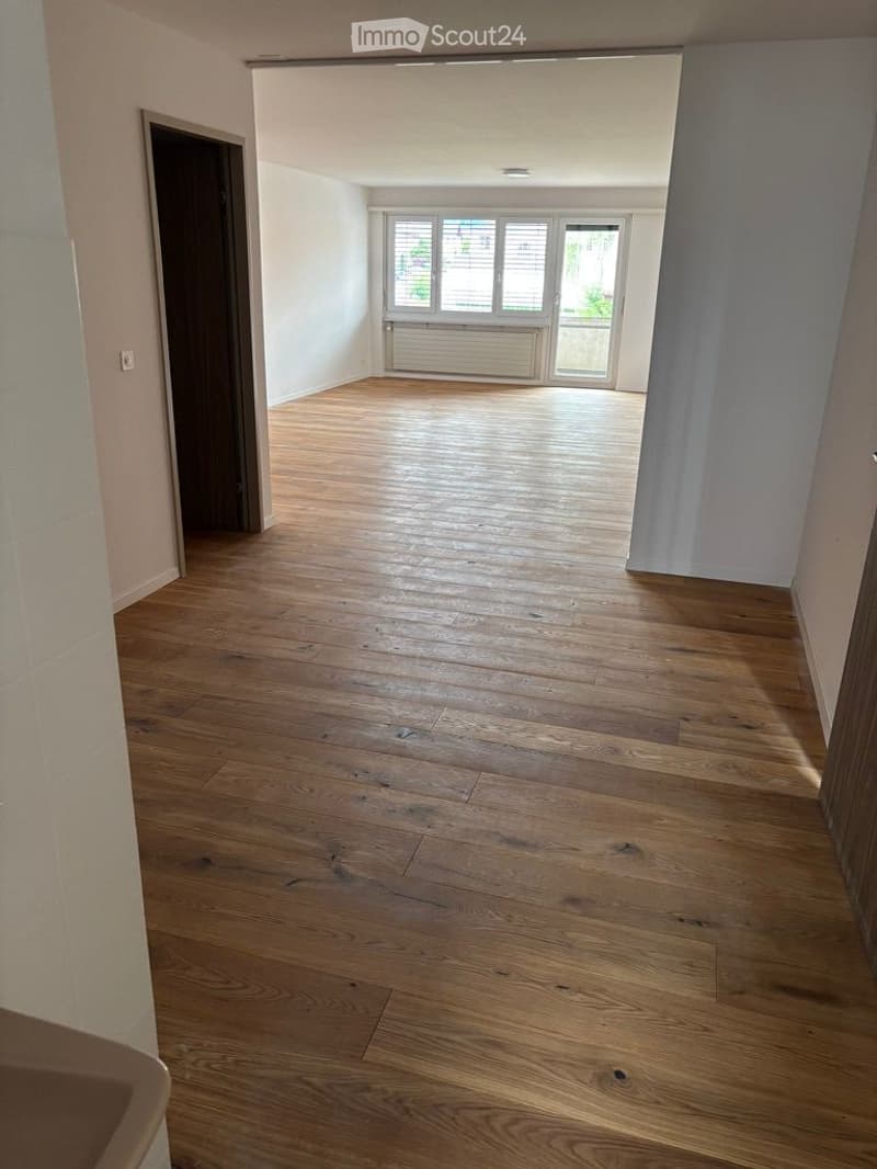 Empty room with wooden flooring, white walls, and large windows with blinds. No furniture or equipment present.