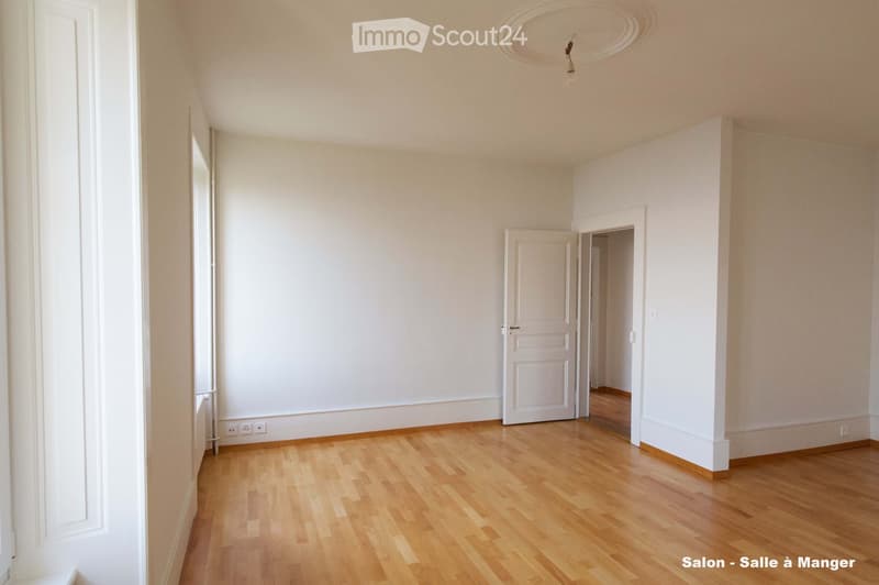 Empty room with light wooden flooring, white walls, and a single door leading to another space. The room has a simple, clean design with no furniture or decorations.