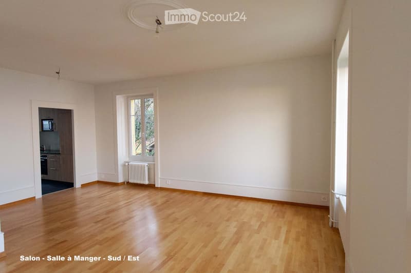 Empty room with wooden flooring, white walls, and large windows. No furniture or equipment present.