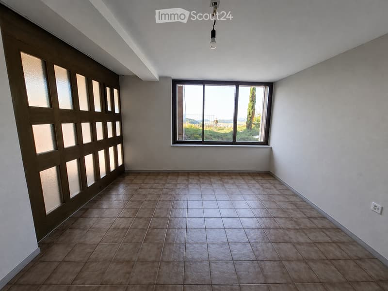 Empty room with tiled floor, large window, and a door with glass panels.