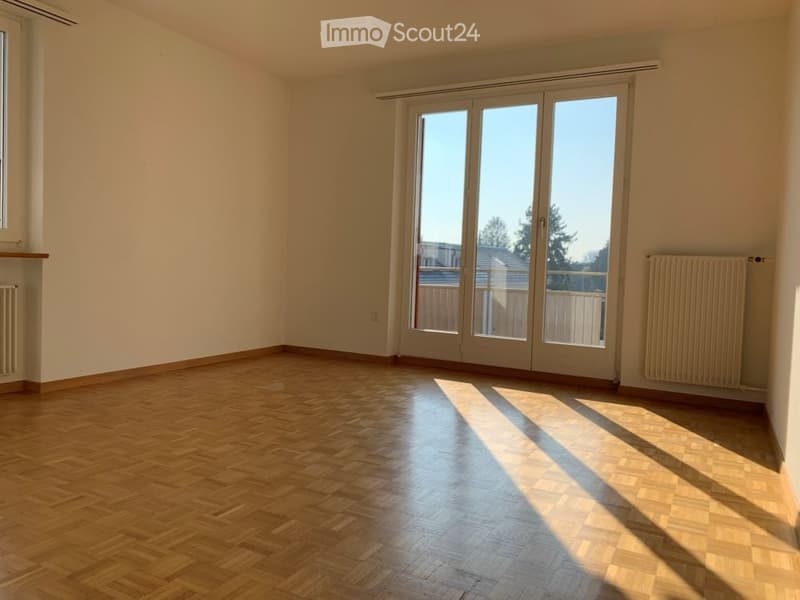 Empty room with wooden flooring, large sliding glass doors, and radiators on both sides.