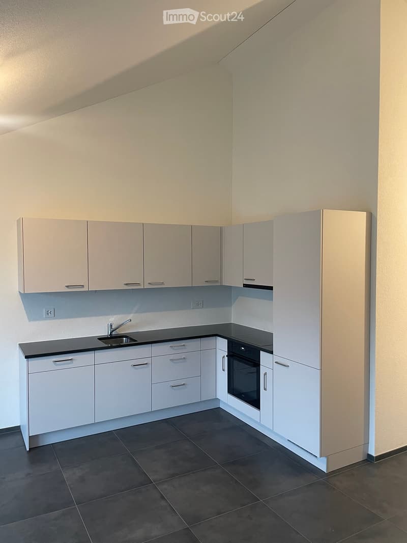 Modern kitchen with white cabinets, dark countertops, and a built-in oven. Features a sink with a modern faucet and ample storage space.