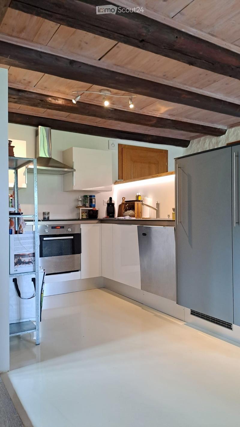 Modern kitchen with white cabinets, stainless steel appliances, and exposed wooden beams on the ceiling.