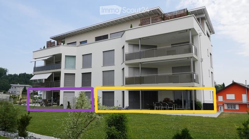 Modern multi-story apartment building with white facade, multiple balconies, and a well-maintained lawn in front.