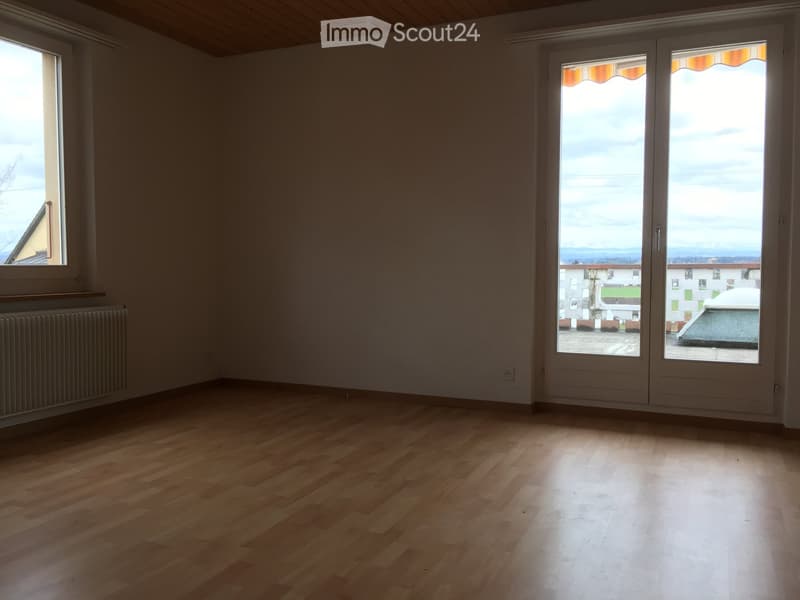 Empty room with wooden flooring, large sliding glass doors, and a radiator on the wall.