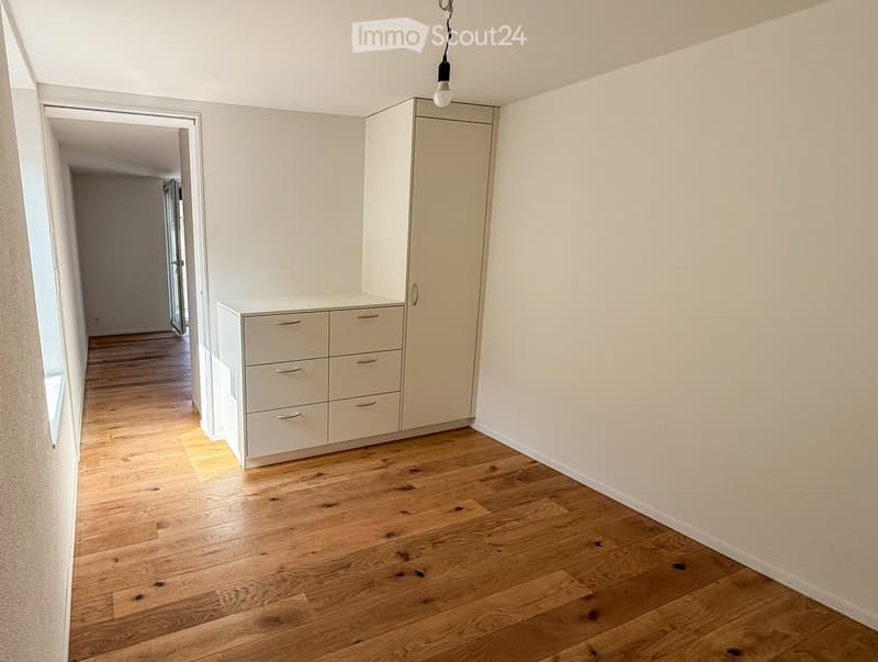 Empty room with light wooden flooring, white walls, and built-in storage units including a tall cabinet and a set of drawers.
