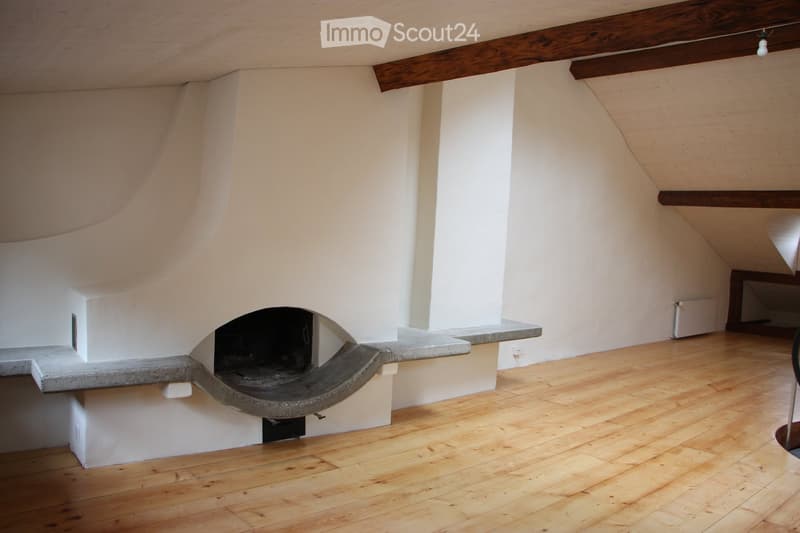 Empty room with wooden flooring, white walls, and a built-in fireplace with stone surround.