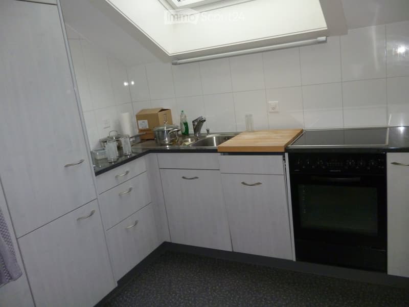 Modern kitchen with white cabinets, stainless steel sink, oven, and various kitchen items on the counter.