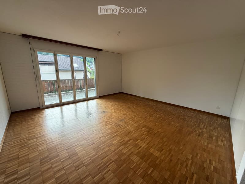 Empty room with wooden flooring and large sliding glass doors leading to a balcony or outdoor area.