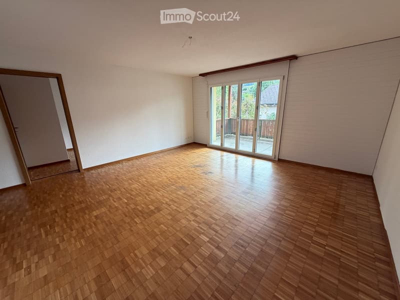 Empty room with wooden flooring, white walls, and large sliding glass doors leading to an outdoor area.
