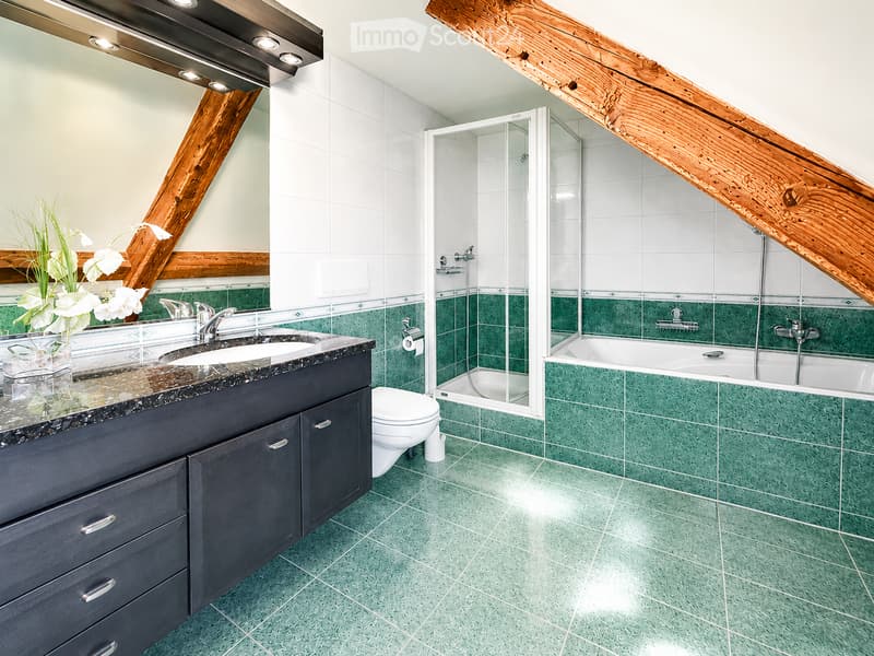 Modern bathroom with green tiles, dark wooden vanity, double sink, bathtub, and shower area.