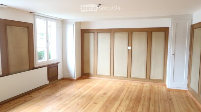 Empty room with wooden flooring, white walls, and large windows. No furniture or equipment present.