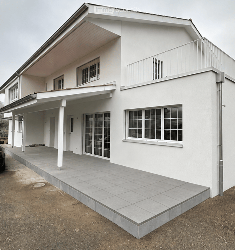 Two-story white house with a covered porch, large windows, and a tiled walkway leading to the entrance.
