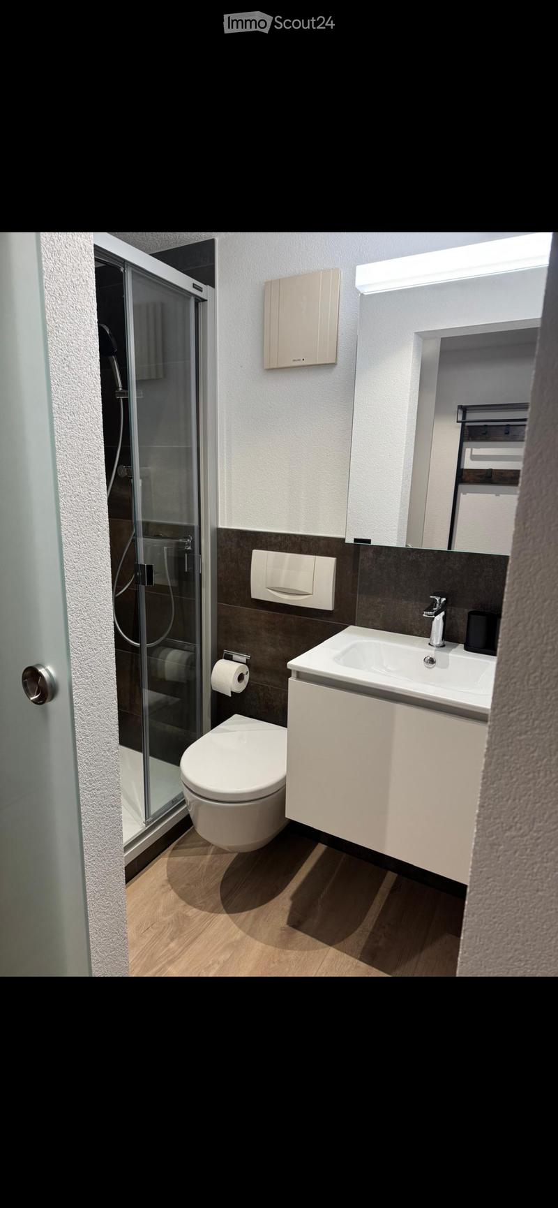 Modern bathroom with white fixtures, glass walk-in shower, toilet, sink with faucet, roll of toilet paper, and mirror