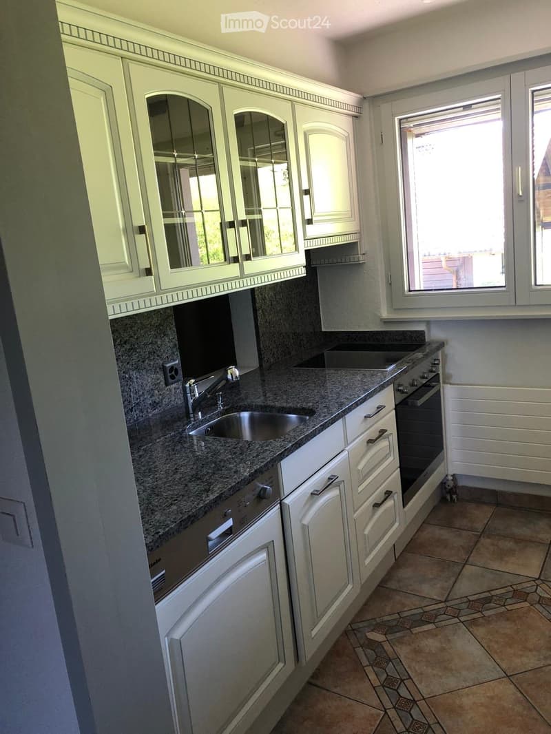 Modern kitchen with white cabinets, granite countertop, stainless steel sink and faucet, built-in oven, and dishwasher.