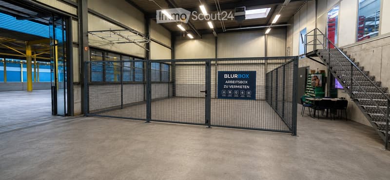 Empty industrial-style room with concrete floor, metal staircase, and a fenced-off area. No furniture or equipment present.