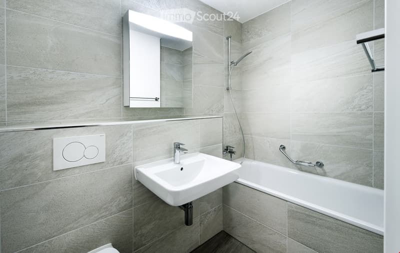 a modern and stylish bathroom with white tiles, a sink, bathtub, shower, mirror, and light fixtures